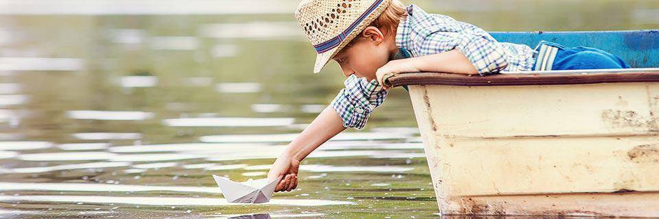 A little boy leans over the side of a boat