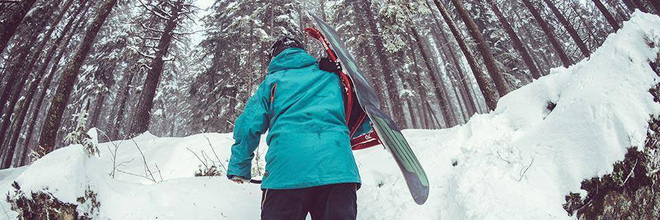 Snowboarder climbing through a forest